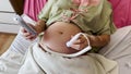 Pregnant woman using fetal Doppler device for listening her baby heartbeat in hospital