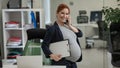 Pregnant woman using mobile phone and holding paper tablet in office. Royalty Free Stock Photo