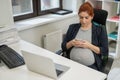 Pregnant woman using mobile phone in office. Royalty Free Stock Photo