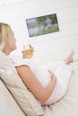 Pregnant woman watching television with a drink Royalty Free Stock Photo