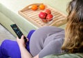 Pregnant woman watching television at home Royalty Free Stock Photo