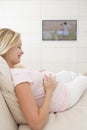 Pregnant woman watching television smiling Royalty Free Stock Photo