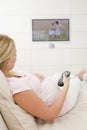 Pregnant woman watching television using remote Royalty Free Stock Photo