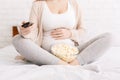 Pregnant woman watching TV and eating popcorn Royalty Free Stock Photo