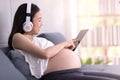 A pregnant woman wear headphones Listen to music and online shopping via smart phone Royalty Free Stock Photo