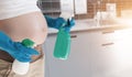 Pregnant woman wearing blue gloves cleaning the toilet.