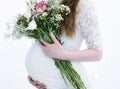 Pregnant woman in a white dress with a bouquet of flowers Royalty Free Stock Photo
