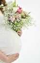 Pregnant woman in a white dress with a bouquet of flowers Royalty Free Stock Photo