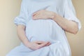 Pregnant woman in white dress holding belly with her hands. Royalty Free Stock Photo