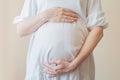 Pregnant woman in white dress holding belly with her hands. Royalty Free Stock Photo