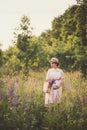 Pregnant woman in white dress holding a straw basket with wildflowers Royalty Free Stock Photo