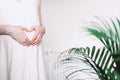 Pregnant woman in white dress making heart on pregnant belly. Maternity, preparation for childbirth, baby Royalty Free Stock Photo