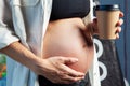 Pregnant woman in white silk shirt and black bra holding a cup of coffee. Royalty Free Stock Photo