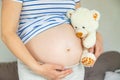 Pregnant woman and white teddy bear. Selective focus Royalty Free Stock Photo