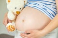 Pregnant woman and white teddy bear. Selective focus Royalty Free Stock Photo