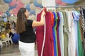 Pregnant woman worker sales manager cleaning dress in a clothing store.