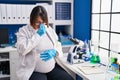 Pregnant woman working at scientist laboratory tired rubbing nose and eyes feeling fatigue and headache Royalty Free Stock Photo