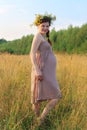 Pregnant woman in wreath poses in dry grass at summer day Royalty Free Stock Photo