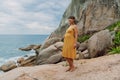 Pregnant woman in yellow dress at summer ocean coastline