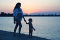 Pregnant woman with a young child walking along the sandy beach at sunset Royalty Free Stock Photo