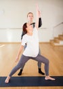 Pregnant woman is engaged in yoga with an instructor. Viparita Virabhadrasana or Reverse Warrior Pose Royalty Free Stock Photo