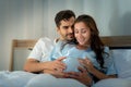 Pregnant woman with husband in bedroom with the atmosphere of having fun talking