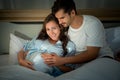 Pregnant woman with husband in bedroom with the atmosphere of having fun talking