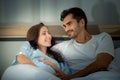 Pregnant woman with husband in bedroom with the atmosphere of having fun talking