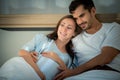 Pregnant woman with husband in bedroom with the atmosphere of having fun talking