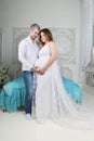 Pregnant woman in long dress and man stand together