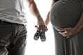 Pregnant woman and man holding baby shoes Royalty Free Stock Photo