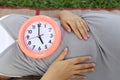 Pregnant women show clock on her belly to tell the time. Royalty Free Stock Photo