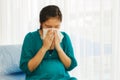 An unhealthy pregnant woman causes complications of the common cold, holding a tissue over her nose.