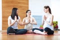 Pregnant women in yoga class sitting on mats stretching arms in a fitness studio