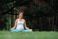 Pregnant yoga in the lotus position on the forest background. in the park the grass mat, outdoor, health woman. Royalty Free Stock Photo