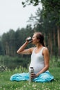 Pregnant yoga in the lotus position with thermos drinking tea. in the park on the grass , outdoor, health woman, female. Royalty Free Stock Photo