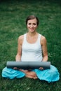 Pregnant yoga woman in the lotus position with mat portrait in park on the grass, breathing, stretching, statics. Royalty Free Stock Photo