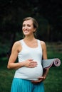 Pregnant yoga woman with mat portrait in park on the grass, breathing, stretching, statics. outdoor, forest. Royalty Free Stock Photo