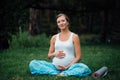 Pregnant yoga woman with mat portrait in park on the grass, breathing, stretching, statics. outdoor, forest. Royalty Free Stock Photo