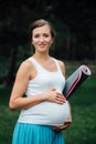 Pregnant yoga woman with mat portrait in park on the grass, breathing, stretching, statics. outdoor, forest. Royalty Free Stock Photo