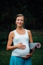 Pregnant yoga woman with mat portrait in park on the grass, breathing, stretching, statics. outdoor, forest. Royalty Free Stock Photo