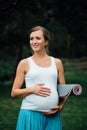 Pregnant yoga woman with mat portrait in park on the grass, breathing, stretching, statics. outdoor, forest. Royalty Free Stock Photo