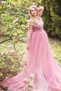 Pregnant young beautiful woman in pink lace long dress in a flowering garden Royalty Free Stock Photo