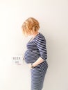 Pregnant young caucasian female touching her growing belly and holding a sign with 40 weeks