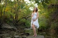 Pregnant young lady laughing holding 9 month expecting belly standing on creek bed in forest Royalty Free Stock Photo