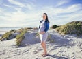 Pregnant young mother to be, standing outdoors looking at camera, beach scene