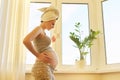 Pregnant young woman with bath towel on head with cup of tea looking out window Royalty Free Stock Photo