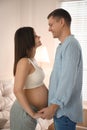 Pregnant young woman with big belly and her husband holding hands together at home Royalty Free Stock Photo