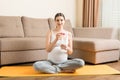 Pregnant young woman with bottle of water while sitting in lotus position on yoga mat. Maintaining water balance at coronavirus Royalty Free Stock Photo
