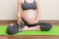 Pregnant young woman with bottle of water while sitting in lotus position on yoga mat. Maintaining water balance at coronavirus Royalty Free Stock Photo